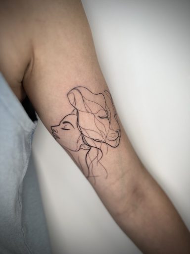 Fine line lioness and lady face tattoo on the upper arm by Lena Luna Tattoo in Letchworth