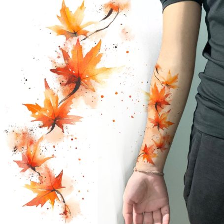 Arm featuring a vibrant tattoo of orange maple leaves and splashes of colour.