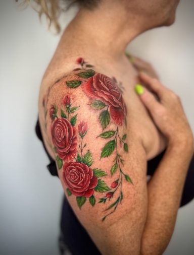 Colour red roses and green leaves shouder tattoo by Lena Luna Tattoo in Hertfordshire