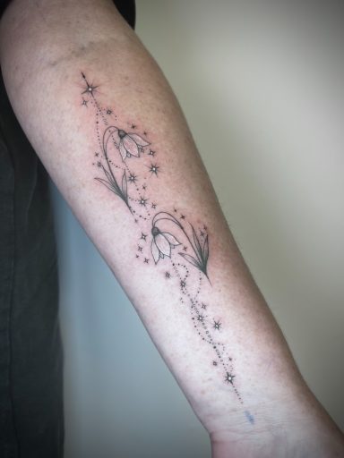 Fine line snowdrop flowers with stars forearm tattoo, dleicate black ink design by Letchworth tattoo artist