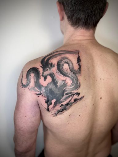 Blackwork dragon back tattoo across shoulder blade by Lena Luna Tattoo in Letchworth