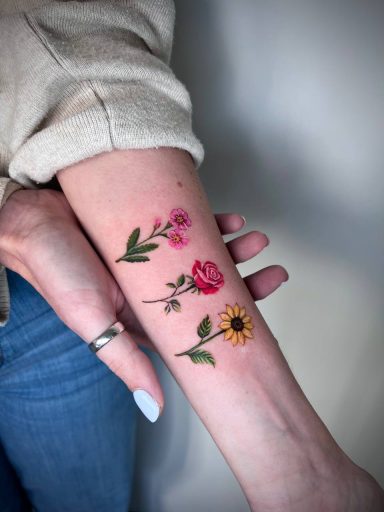 Watercolour floral wrist tattoo with pink flowers and botanical elements by Lena Luna in Letchworth Hertfordshire