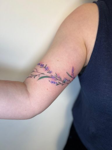 Fine line lavender branch tattoo on the inner arm in soft purple tones by Lena Luna Tattoo in Letchworth, Hertfordshire